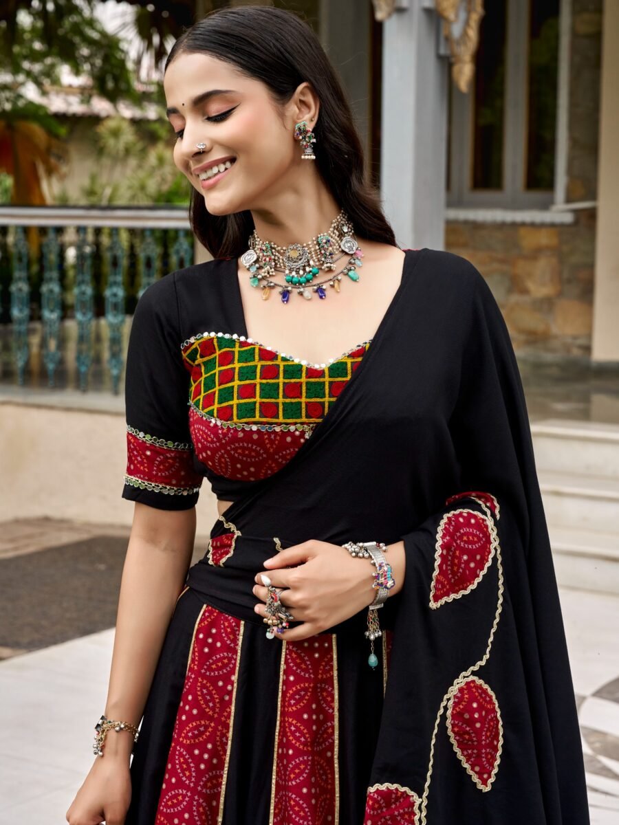 A smiling woman wearing a black and deep red Ajrakh printed lehenga choli with heavy traditional silver jewelry during a festive event.