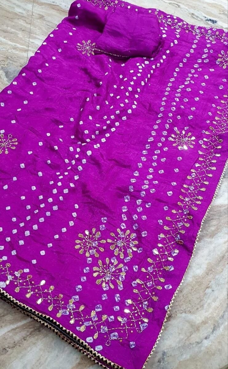 A vibrant magenta Art Silk Bandhani saree adorned with intricate gold Gota Patti embroidery and traditional white tie-dye dots.