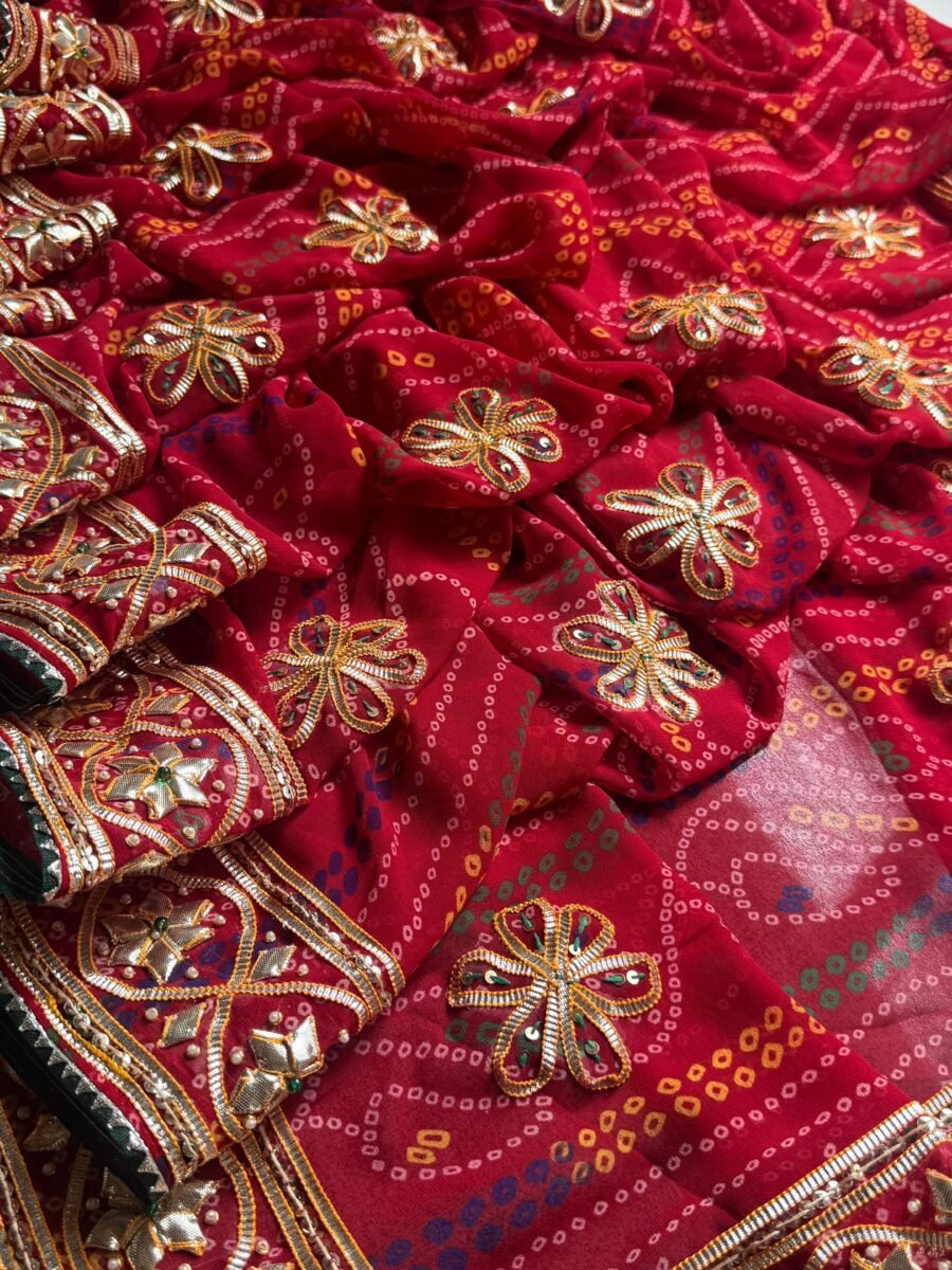 A close-up of a vibrant red Bandhani Georgette saree featuring elaborate gold Gota Patti, moti, and aari tari embroidery.