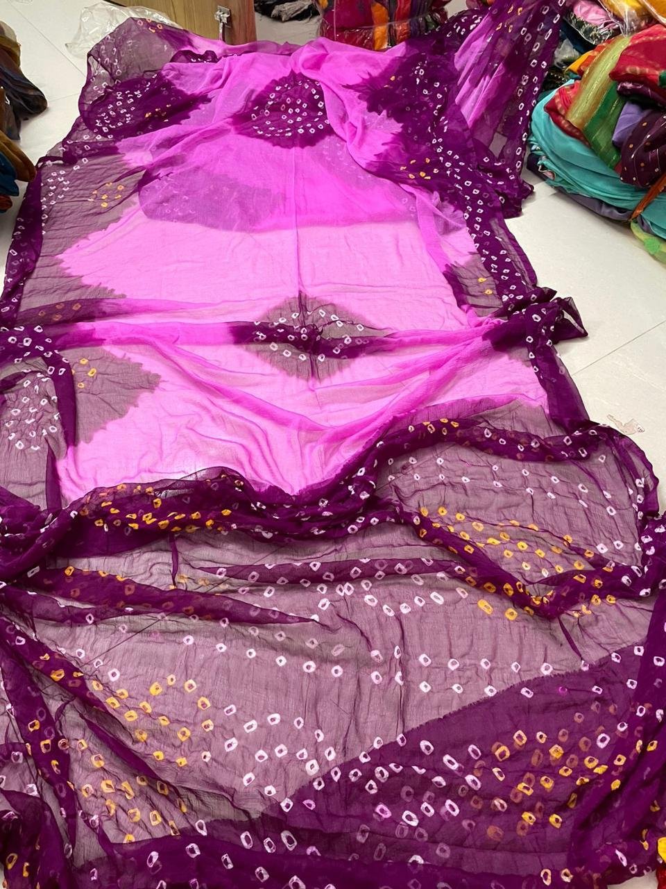 Nazneen Chiffon Hand Tie Dye Bandhani Saree 10 A close-up of a Nazneen Chiffon saree featuring a striking hand tie dye Bandhani pattern in yellow and maroon.