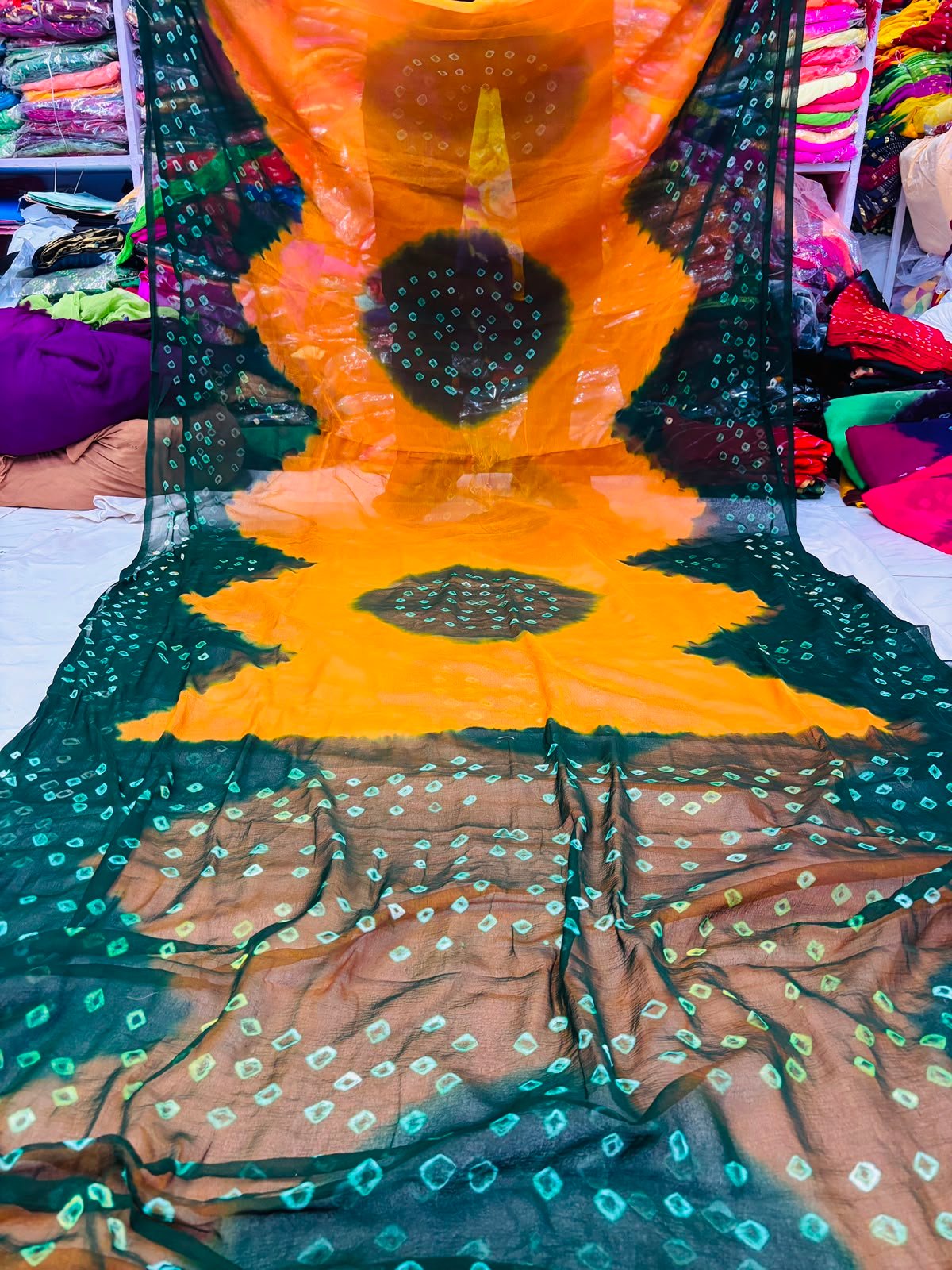 Nazneen Chiffon Hand Tie Dye Bandhani Saree 2 A close-up of a Nazneen Chiffon saree featuring a striking hand tie dye Bandhani pattern in yellow and maroon.