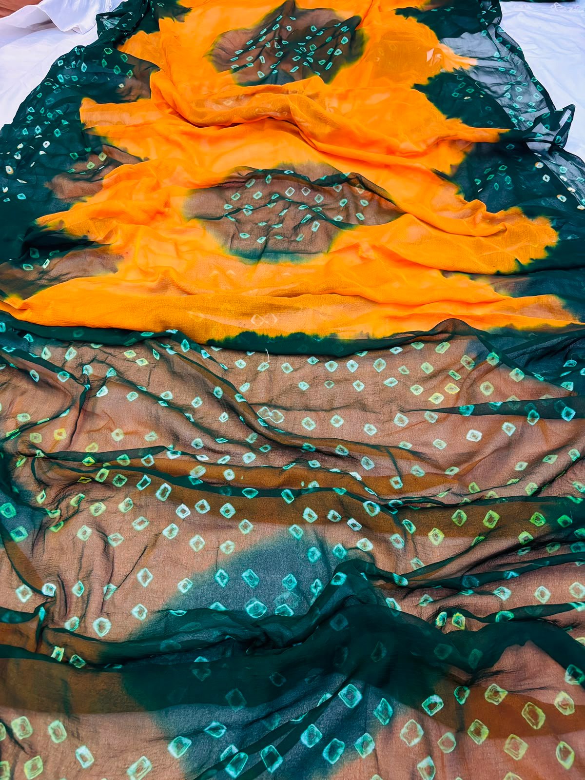 Nazneen Chiffon Hand Tie Dye Bandhani Saree 8 A close-up of a Nazneen Chiffon saree featuring a striking hand tie dye Bandhani pattern in yellow and maroon.