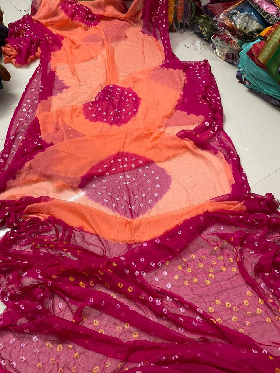 Nazneen Chiffon Hand Tie Dye Bandhani Saree 9 A close-up of a Nazneen Chiffon saree featuring a striking hand tie dye Bandhani pattern in yellow and maroon.