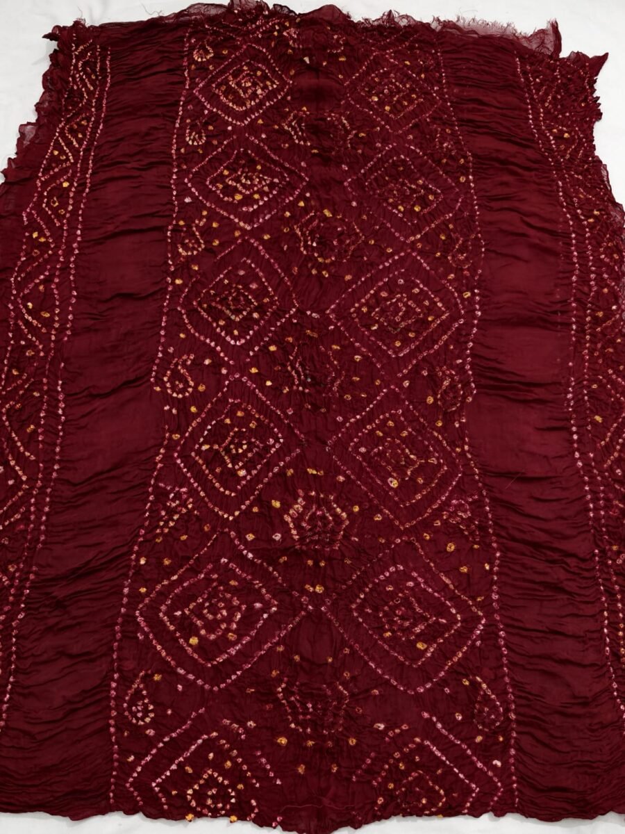 A beautiful deep red Chiffon Georgette Bandhani saree with white patterned motifs spread across the fabric.
