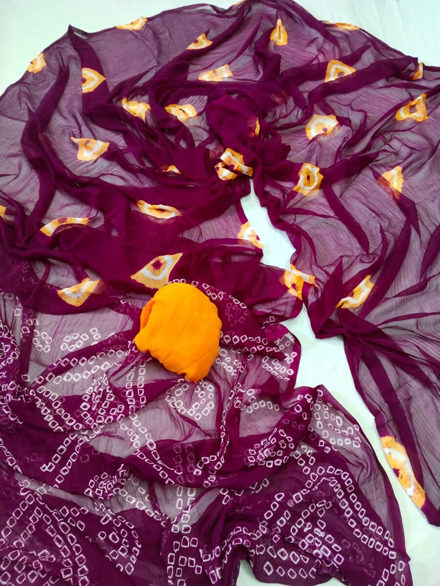 A beautiful deep purple Nazneen chiffon saree with traditional white Bandhani patterns and orange highlights displayed on a white background.