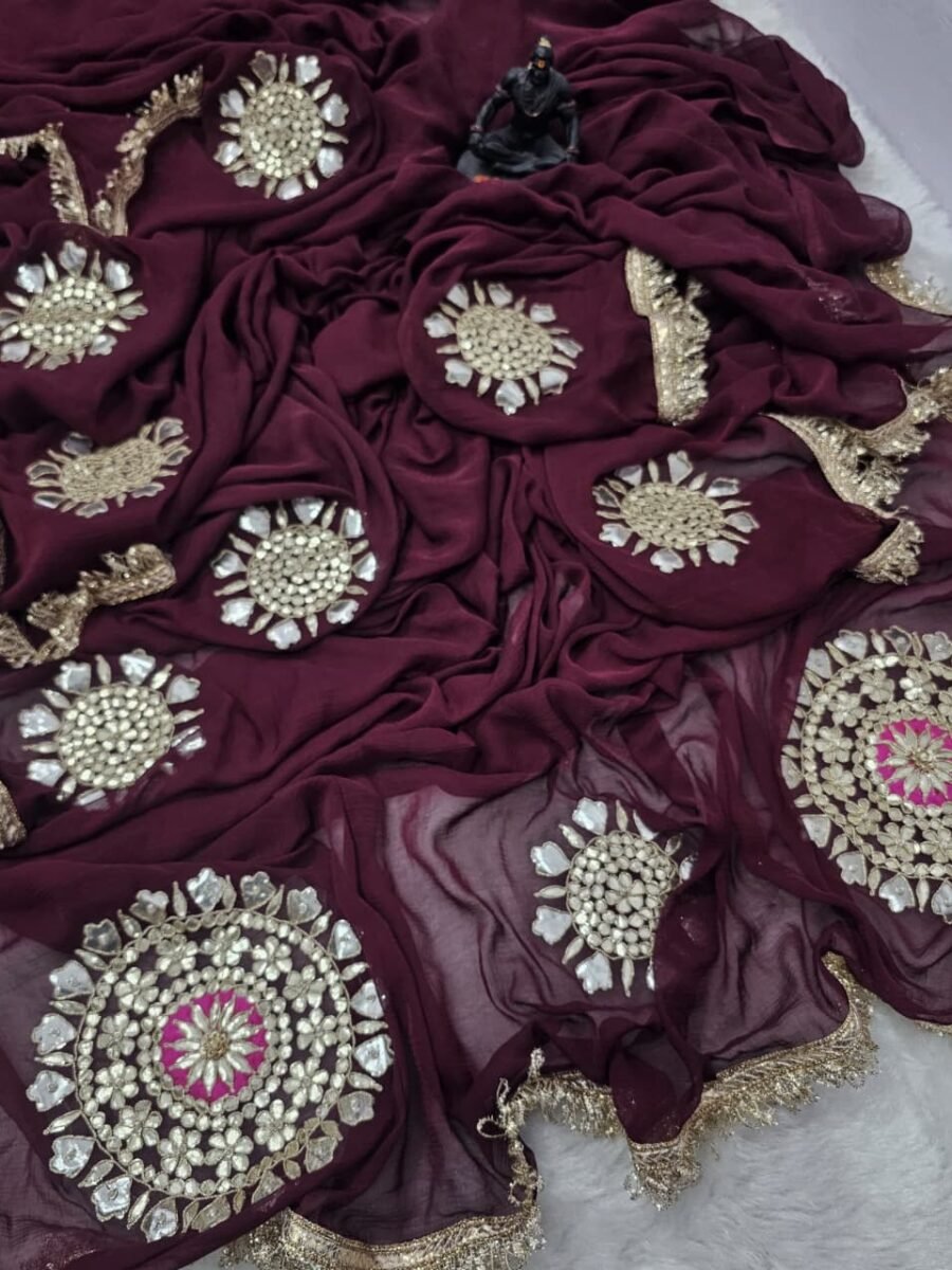 A close-up of a deep maroon Chiffon saree featuring intricate Gota Patti embroidery and mirror-work circular motifs.