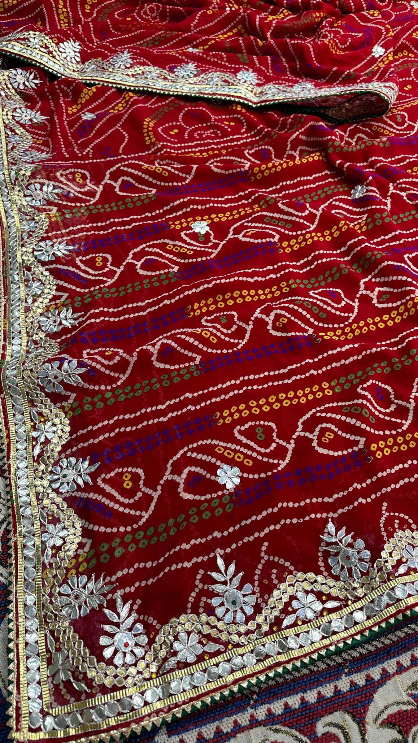 Micro Georgette Chunari Saree with Hand Gota Patti Work 1 A close-up of a red Micro Georgette Chunari Saree featuring detailed Gota Patti border work and traditional bandhani-style patterns.