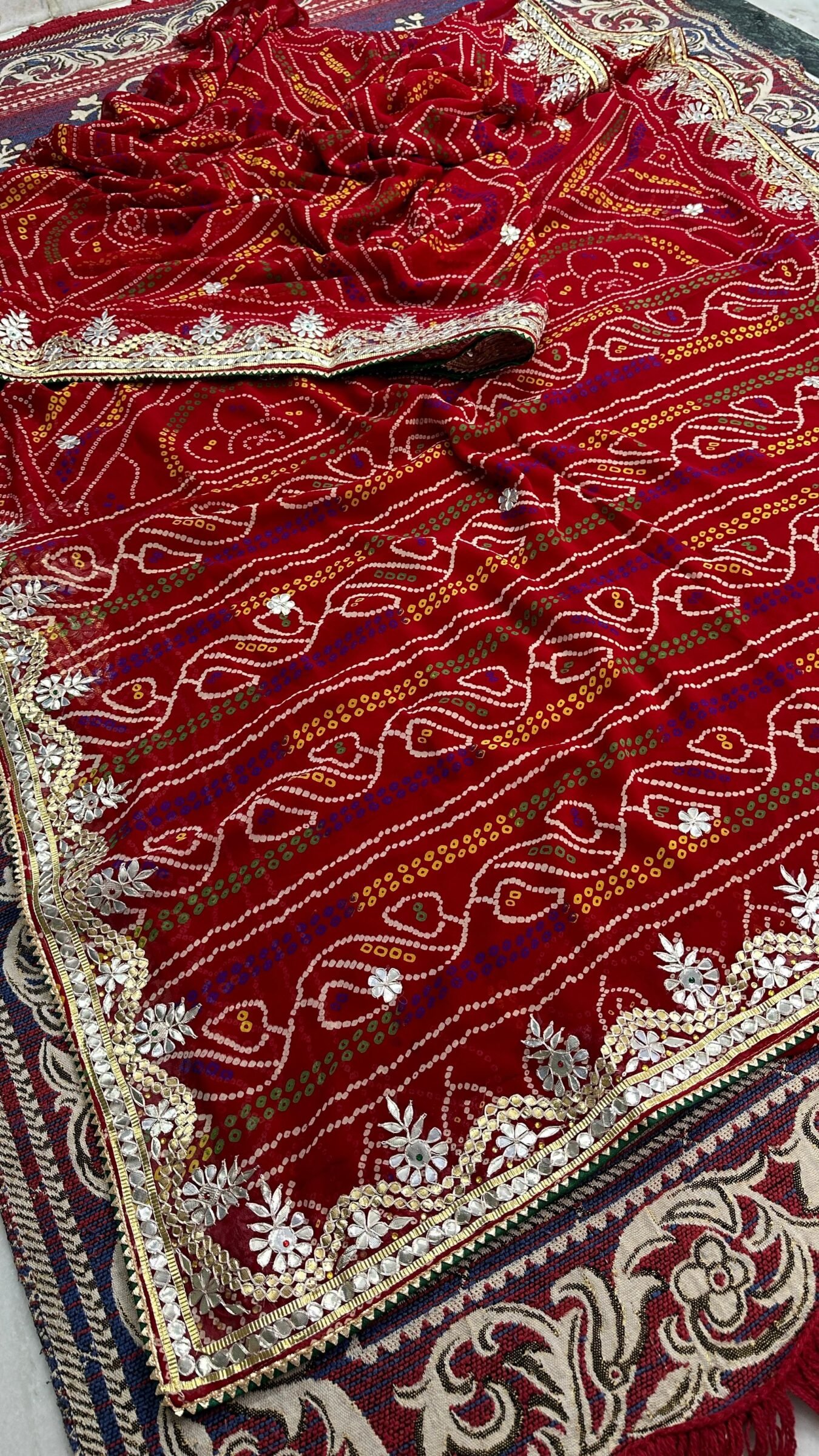 Micro Georgette Chunari Saree with Hand Gota Patti Work 2 A close-up of a red Micro Georgette Chunari Saree featuring detailed Gota Patti border work and traditional bandhani-style patterns.
