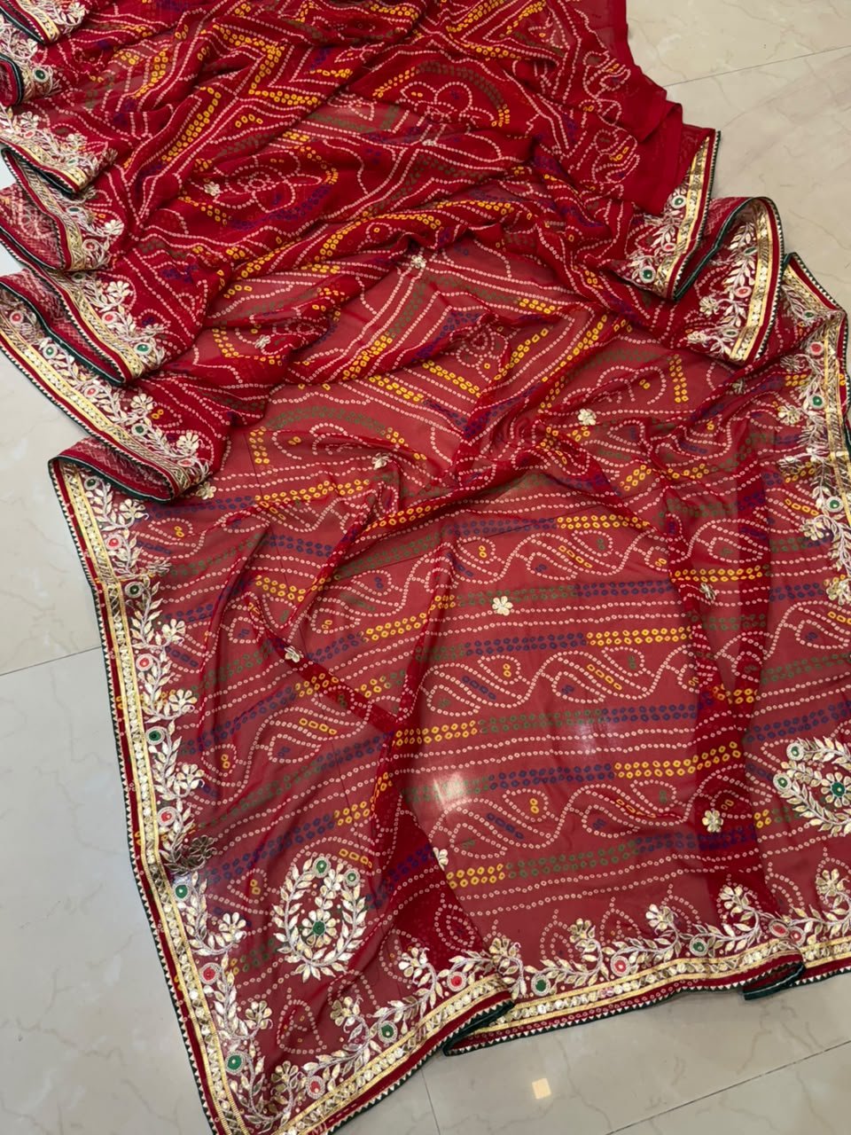 Micro Georgette Chunari Saree with Hand Gota Patti Work 3 A close-up of a red Micro Georgette Chunari Saree featuring detailed Gota Patti border work and traditional bandhani-style patterns.