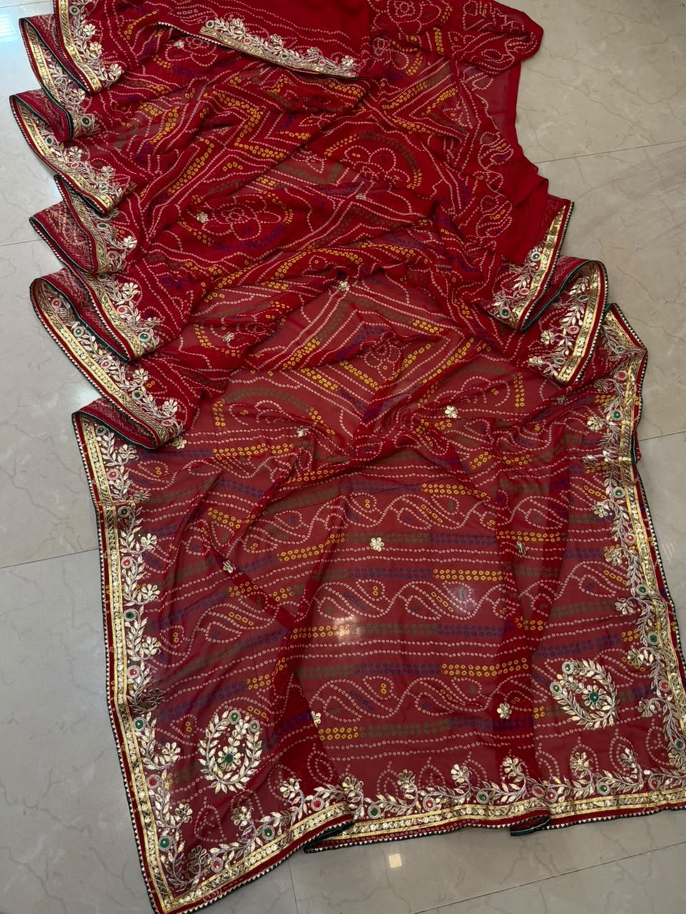 Micro Georgette Chunari Saree with Hand Gota Patti Work 4 A close-up of a red Micro Georgette Chunari Saree featuring detailed Gota Patti border work and traditional bandhani-style patterns.
