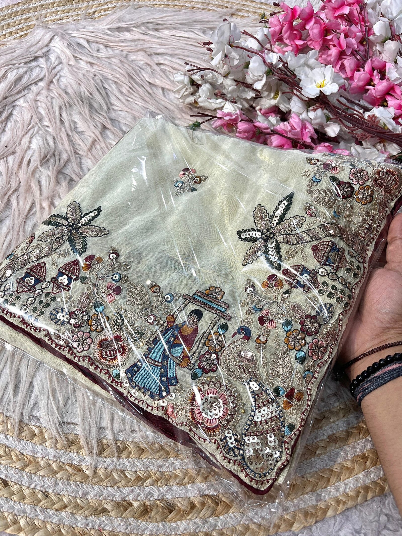 Cosmos Silk Designer Saree with Heavy Thread Embroidery 1 A beautiful Cosmos Silk saree featuring heavy thread embroidery and sequin work with colorful swing and palm tree motifs, presented in packaging.