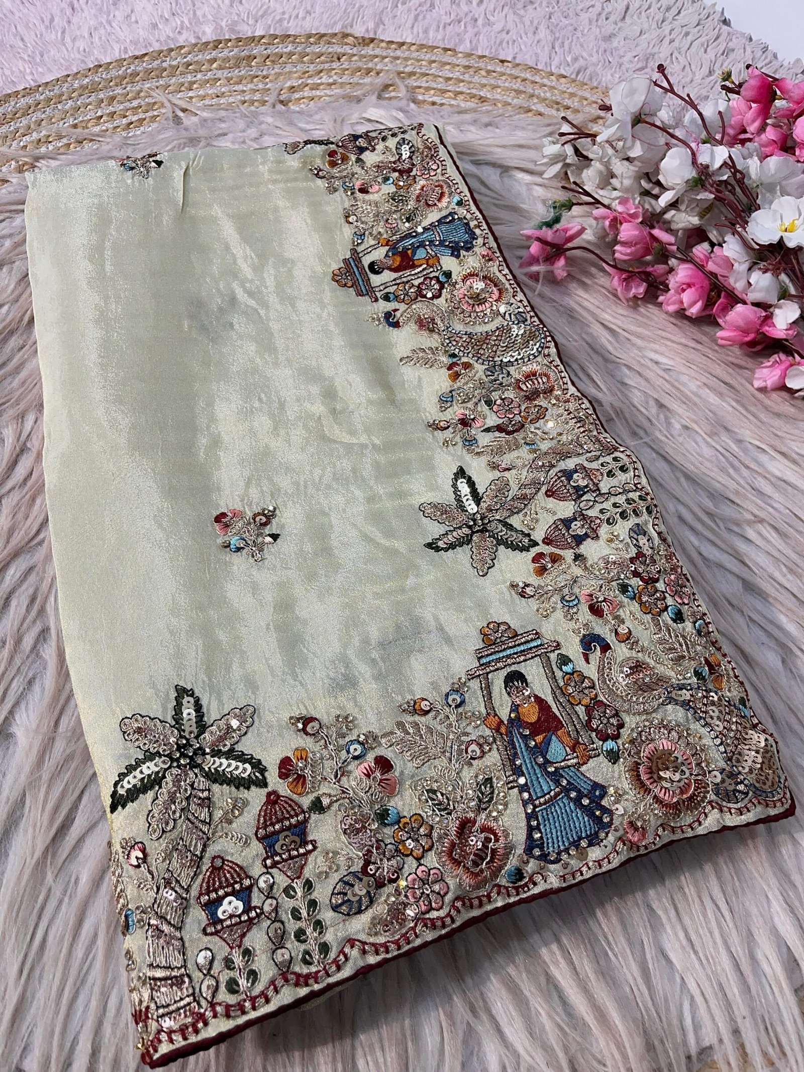 Cosmos Silk Designer Saree with Heavy Thread Embroidery 2 A beautiful Cosmos Silk saree featuring heavy thread embroidery and sequin work with colorful swing and palm tree motifs, presented in packaging.