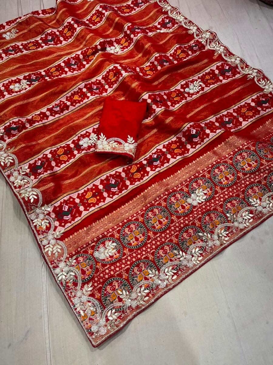 A beautiful red Dola Silk Patola saree with intricate Zardozi handwork border and matching blouse piece.