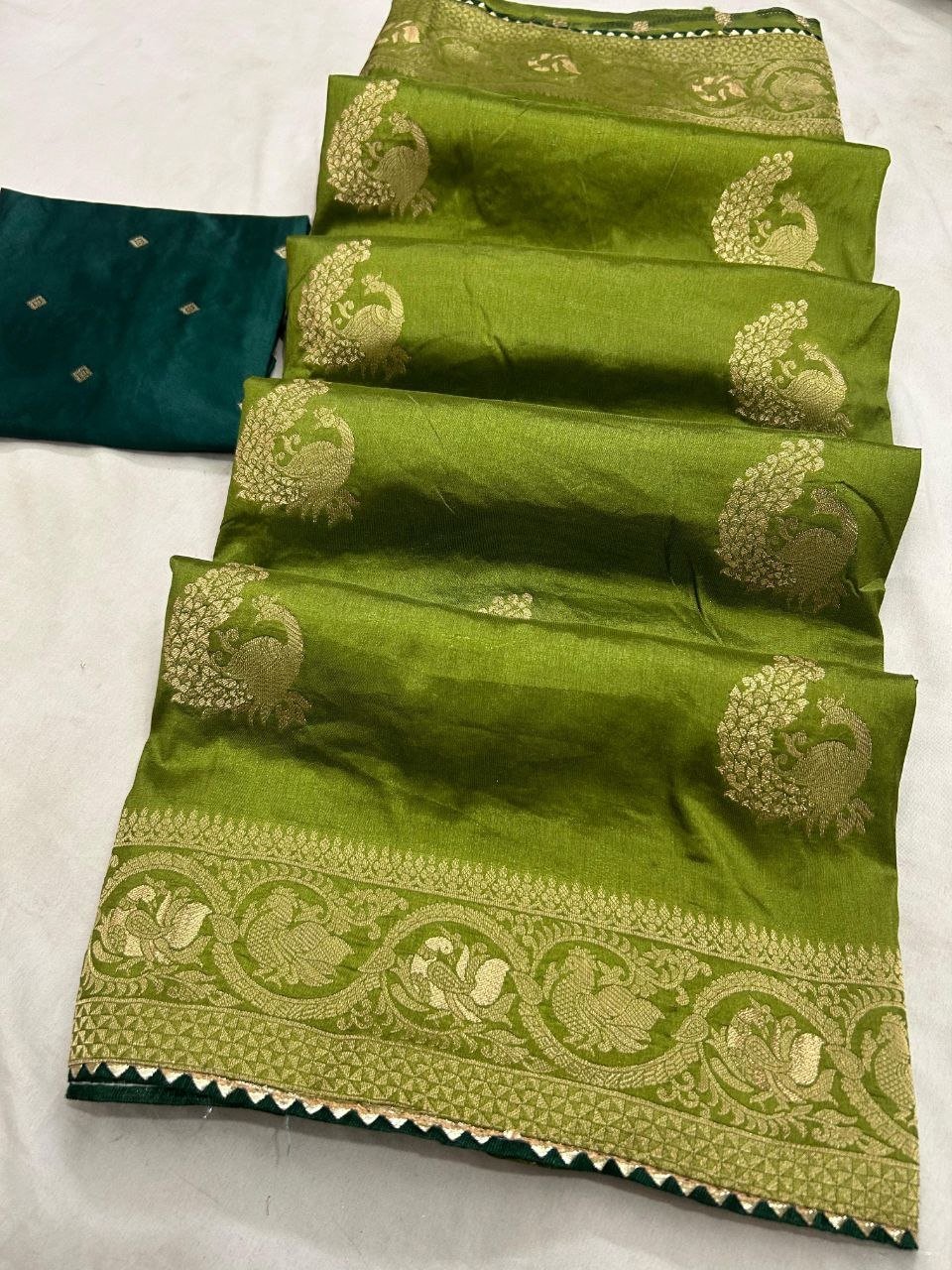 Deep Purple Dola Silk Saree with Peacock Zari Work 2 A beautiful deep purple Dola silk saree displayed in folds, showcasing gold zari peacock motifs and an ornate zari border.