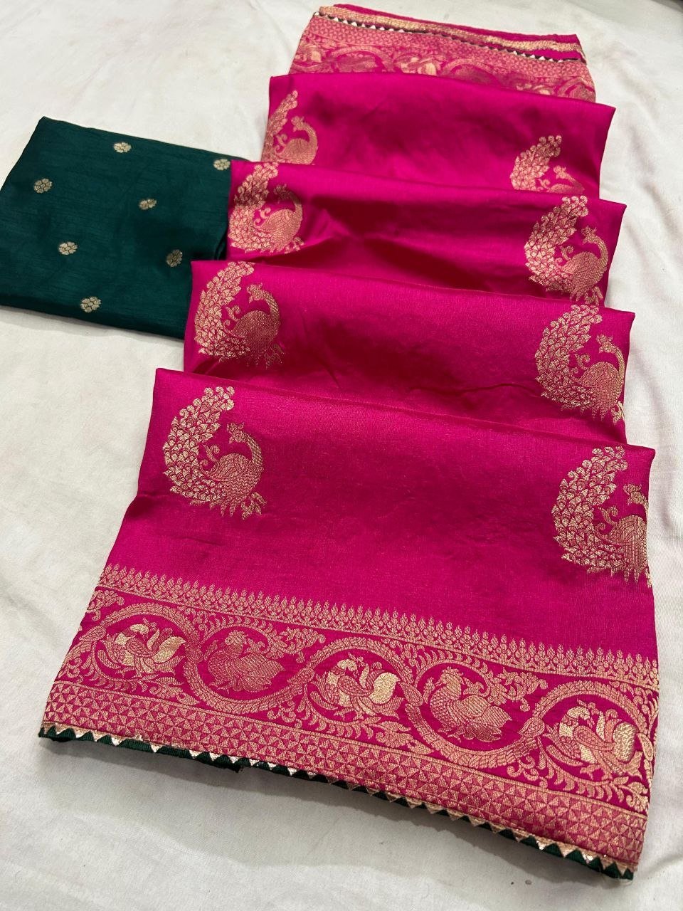 Deep Purple Dola Silk Saree with Peacock Zari Work 4 A beautiful deep purple Dola silk saree displayed in folds, showcasing gold zari peacock motifs and an ornate zari border.