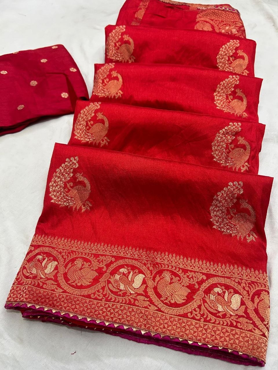 Deep Purple Dola Silk Saree with Peacock Zari Work 5 A beautiful deep purple Dola silk saree displayed in folds, showcasing gold zari peacock motifs and an ornate zari border.