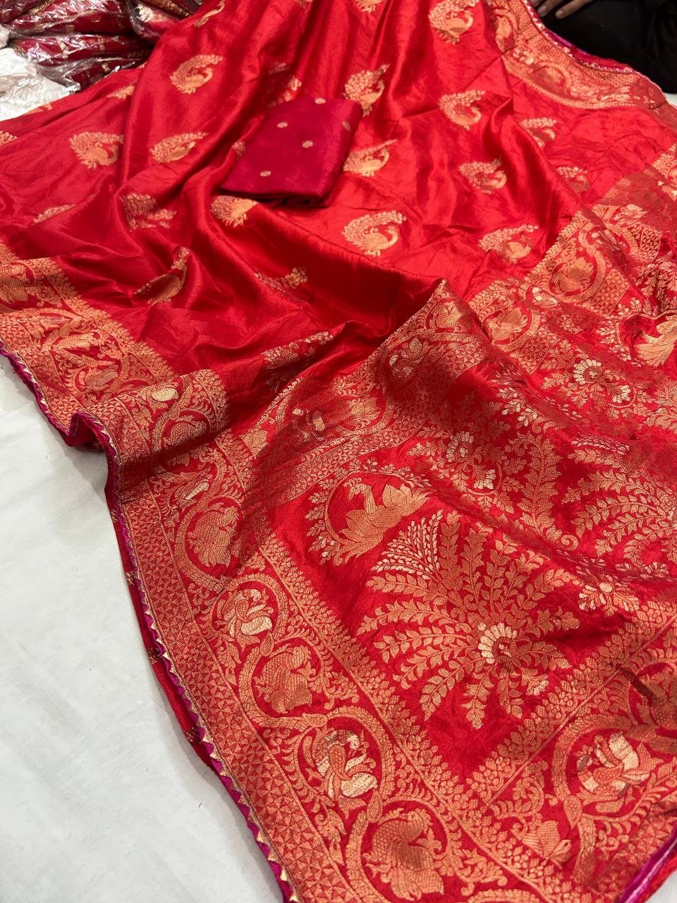 Deep Purple Dola Silk Saree with Peacock Zari Work 7 A beautiful deep purple Dola silk saree displayed in folds, showcasing gold zari peacock motifs and an ornate zari border.