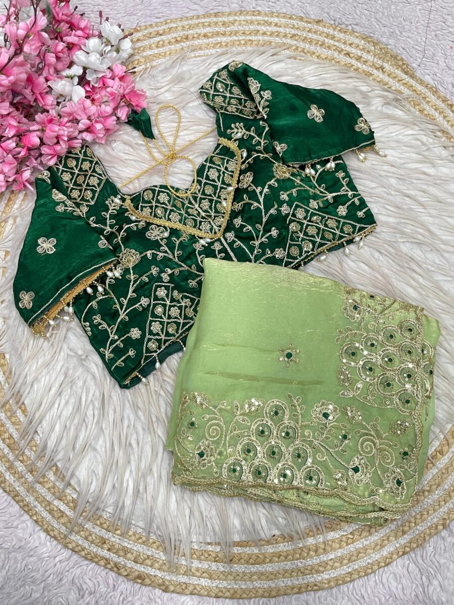 A green Fendy Satin Silk saree paired with a matching embroidered blouse displayed on a decorative woven mat.