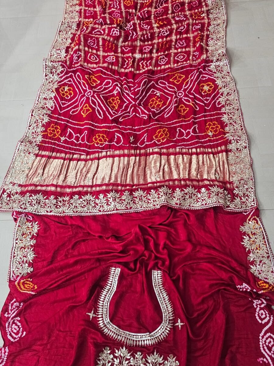 A beautiful deep red pure Gajji silk Ghat Choola Bandhej saree with heavy Gota Patti work and a matching embellished blouse.