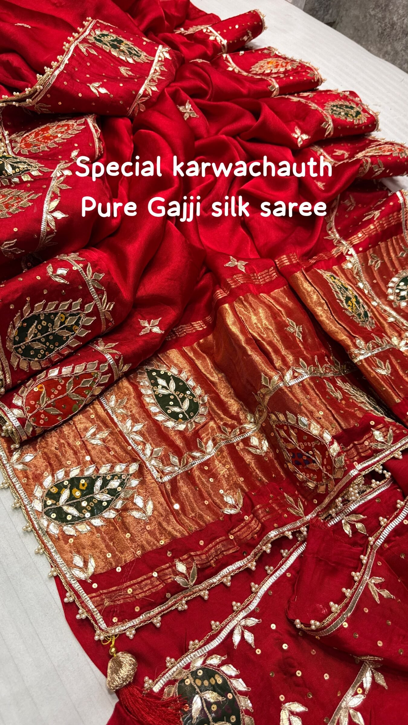 Pure Gajji Silk Saree with Hand Gota Patti Work 1 A close-up view of a vibrant red pure Gajji Silk saree featuring detailed hand Gota Patti Keri work and a decorative designer border.