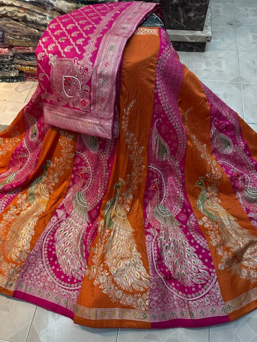 A stunning designer Munga silk lehenga in orange and pink featuring intricate peacock embroidery with katdana and moti work.