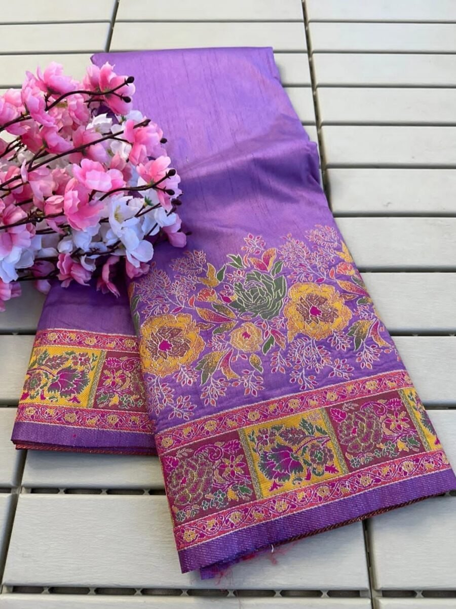 A close-up of a purple Rajwadi Pashmina silk saree with intricate gold Zari borders and floral patterns, presented with decorative pink flowers.