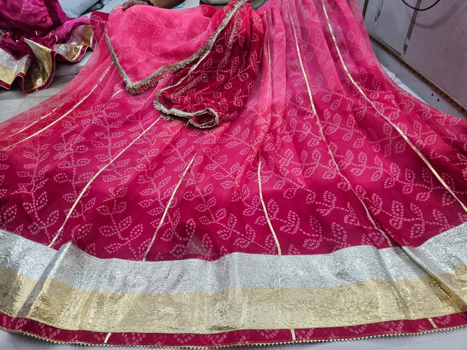 Royal Jorjet Bandhani Lehenga with Lappa Lace Border 2 A yellow and orange Bandhani lehenga featuring a wide silver and gold Lappa lace border on display.