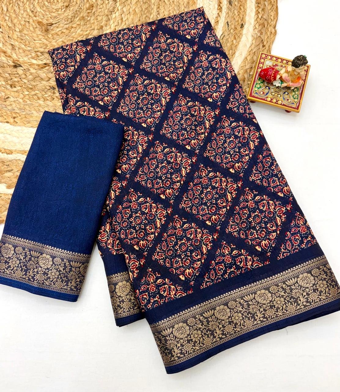 Soft Dola Weaving Saree with Jacquard Border 1 A navy blue Soft Dola weaving saree with an intricate golden jacquard border and a matching blouse piece on a jute mat.