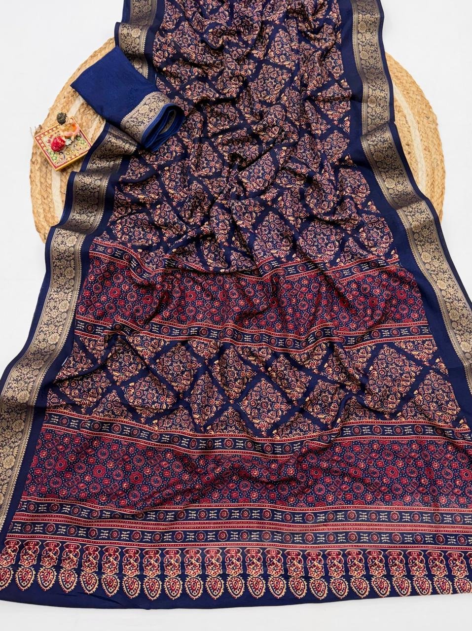 Soft Dola Weaving Saree with Jacquard Border 10 A navy blue Soft Dola weaving saree with an intricate golden jacquard border and a matching blouse piece on a jute mat.