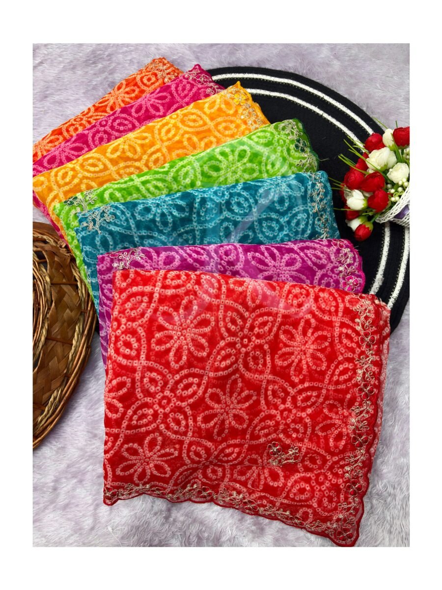 A stack of vibrant Ajarkh print soft satin silk sarees with mirror work detail displayed on a white textured background.