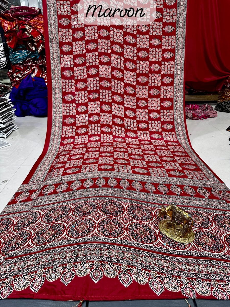 A maroon Ajarkh print soft satin silk saree displayed with a golden statue of a bull, featuring intricate mirror work and traditional patterns.