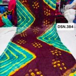 A person holding up a vibrant art silk Bandhani saree with geometric patterns and bright tie-dye work.