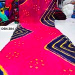 A person holding up a vibrant art silk Bandhani saree with geometric patterns and bright tie-dye work.