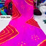 A person holding up a vibrant art silk Bandhani saree with geometric patterns and bright tie-dye work.