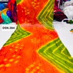 A person holding up a vibrant art silk Bandhani saree with geometric patterns and bright tie-dye work.