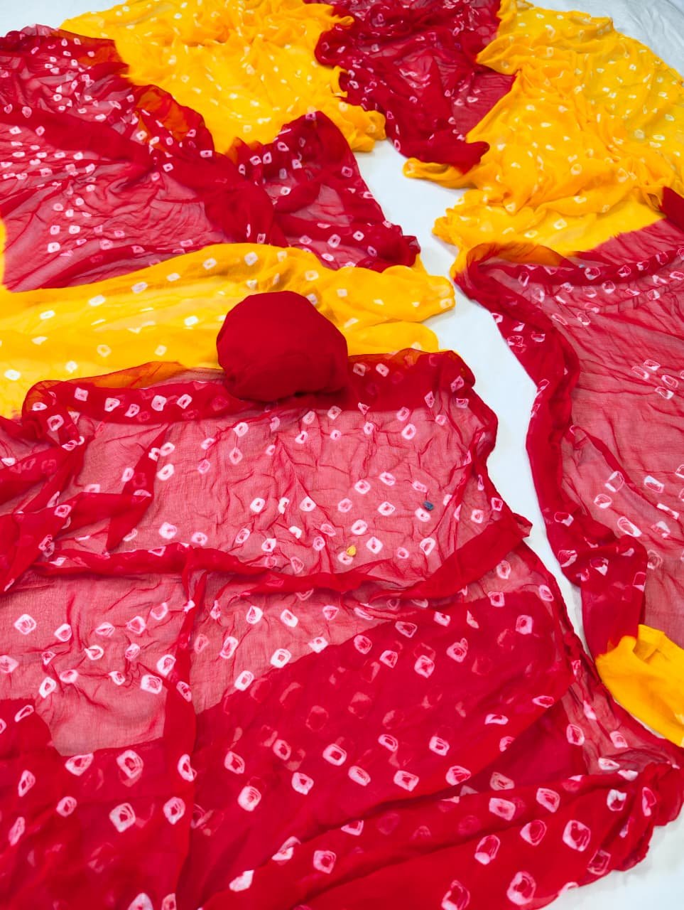Nazneen Chiffon Bandhani Saree 1 A close-up of a Nazneen Chiffon Bandhani Saree featuring vibrant red and yellow tie and dye patterns.