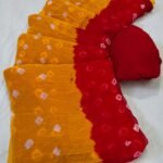 A close-up of a Nazneen Chiffon Bandhani Saree featuring vibrant red and yellow tie and dye patterns.