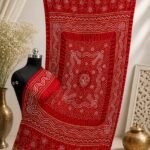A red pure Gajji silk Bandhani dupatta with gold borders displayed on a mannequin.