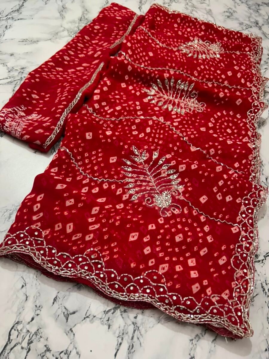 New Arrivals 34 A close-up view of a vibrant red synthetic georgette saree featuring intricate Bandhani prints, silver handwork motifs, and an elaborate cutwork border.