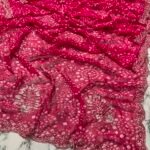 A close-up view of a vibrant red synthetic georgette saree featuring intricate Bandhani prints, silver handwork motifs, and an elaborate cutwork border.