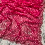 A close-up view of a vibrant red synthetic georgette saree featuring intricate Bandhani prints, silver handwork motifs, and an elaborate cutwork border.