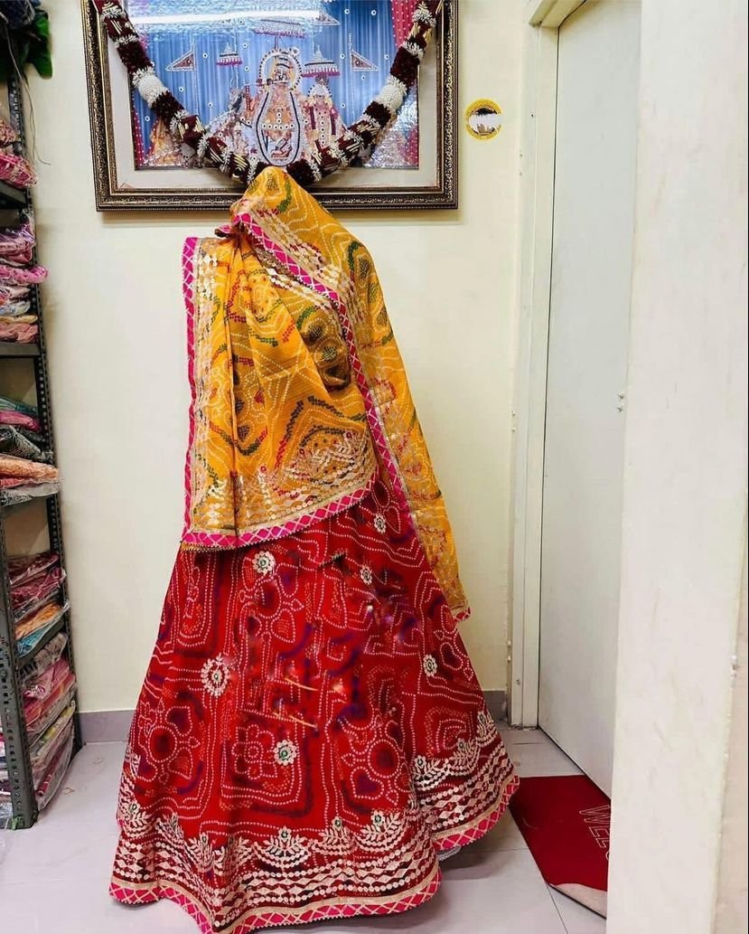 A red and yellow Bandhani lehenga with Gota Patti work displayed on a mannequin.