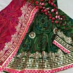 A red and yellow Bandhani lehenga with Gota Patti work displayed on a mannequin.