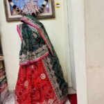 A red and yellow Bandhani lehenga with Gota Patti work displayed on a mannequin.