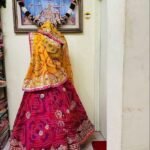 A red and yellow Bandhani lehenga with Gota Patti work displayed on a mannequin.