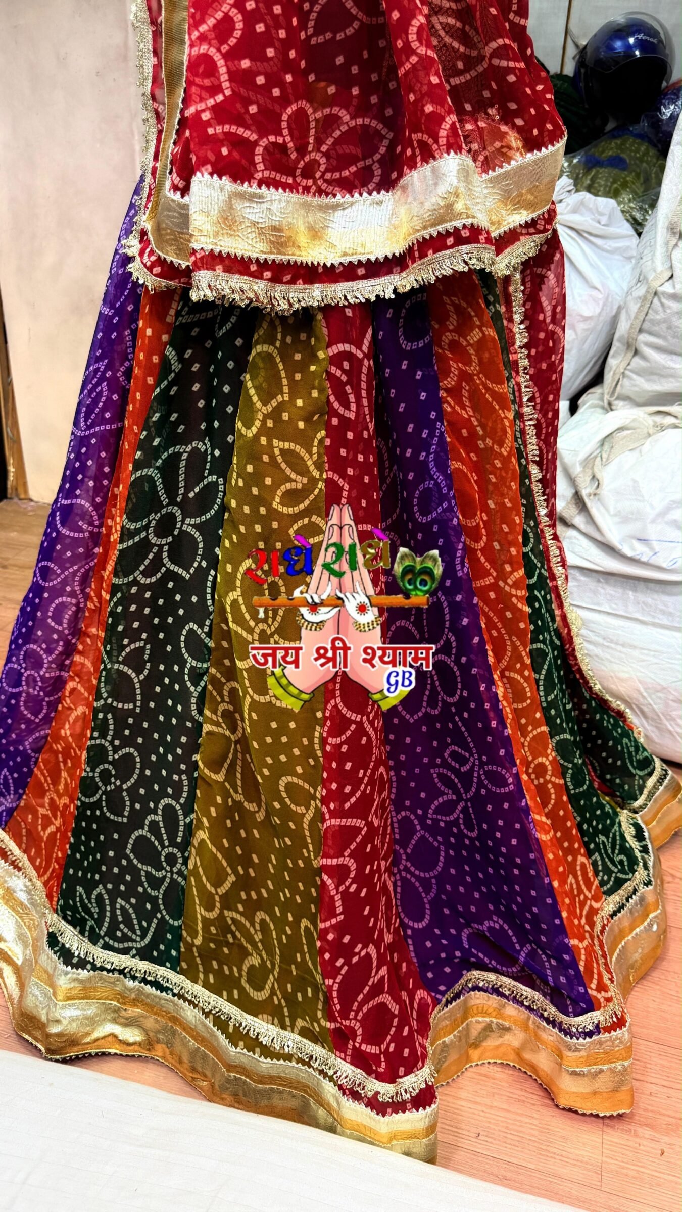 Royal Georgette Bandhani Lehenga with Gota Patti Work 4 A multi-colored Bandhani lehenga with a red dupatta and heavy gota patti border displayed on a mannequin in a traditional architectural setting.