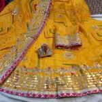 A red and yellow Bandhani lehenga with Gota Patti work displayed on a mannequin.