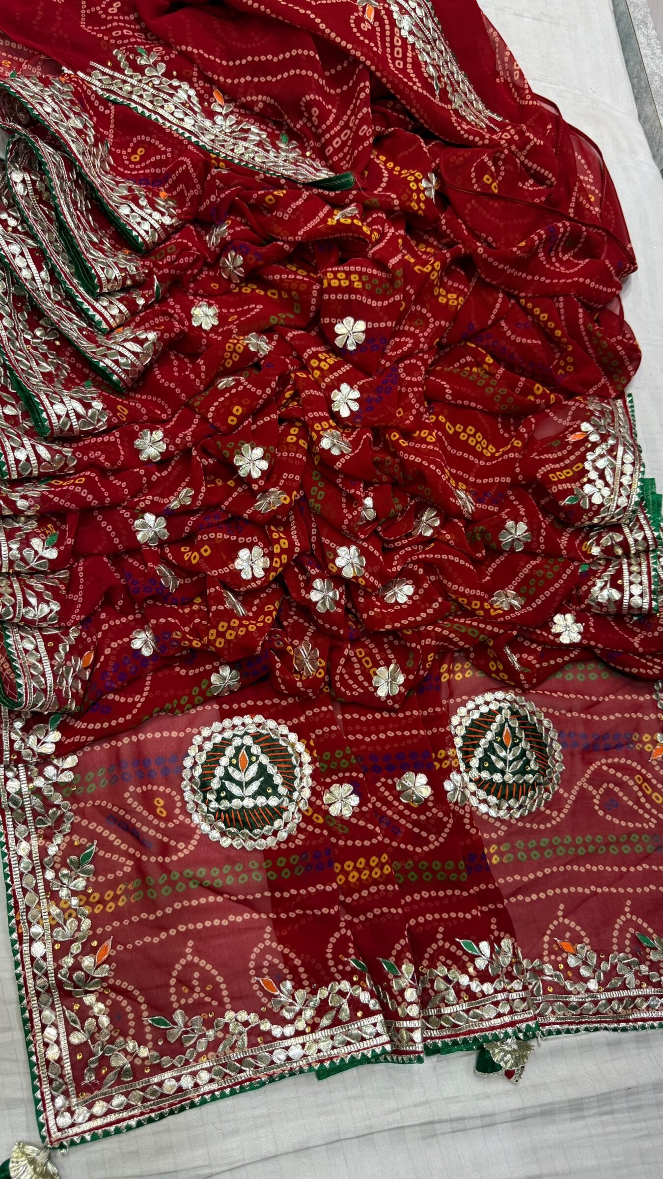 Red Bandhej Georgette Saree With Hand Gota Patti Work 4 A vibrant red Bandhej georgette saree featuring detailed gold Gota Patti peacock motifs and borders.