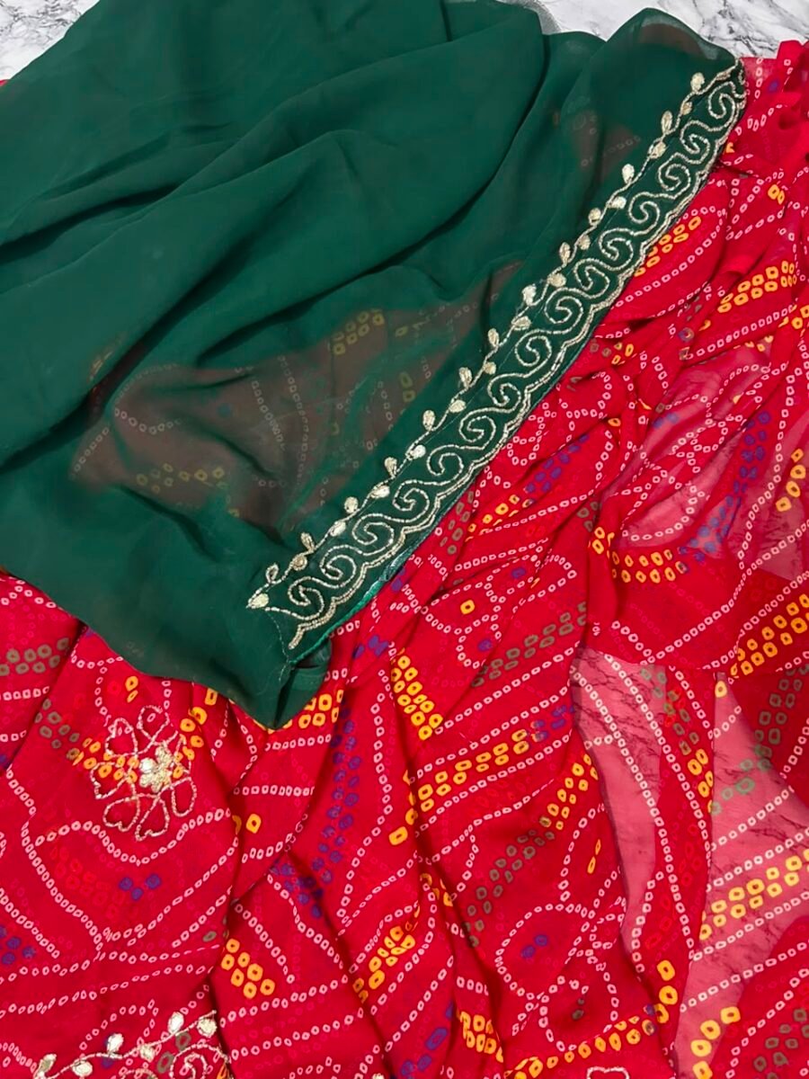 New Arrivals 37 A close-up view of a red and yellow Chunari Bandhej saree with an intricate green border featuring detailed golden handwork.