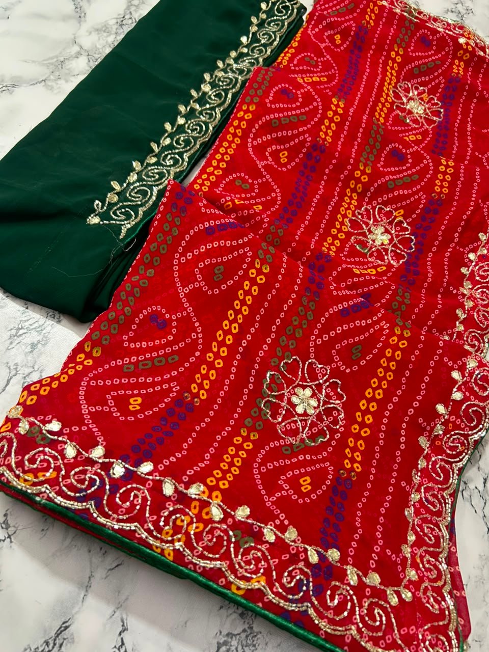 Chunari Bandhej Handwork Synthetic Georgette Saree 2 A close-up view of a red and yellow Chunari Bandhej saree with an intricate green border featuring detailed golden handwork.